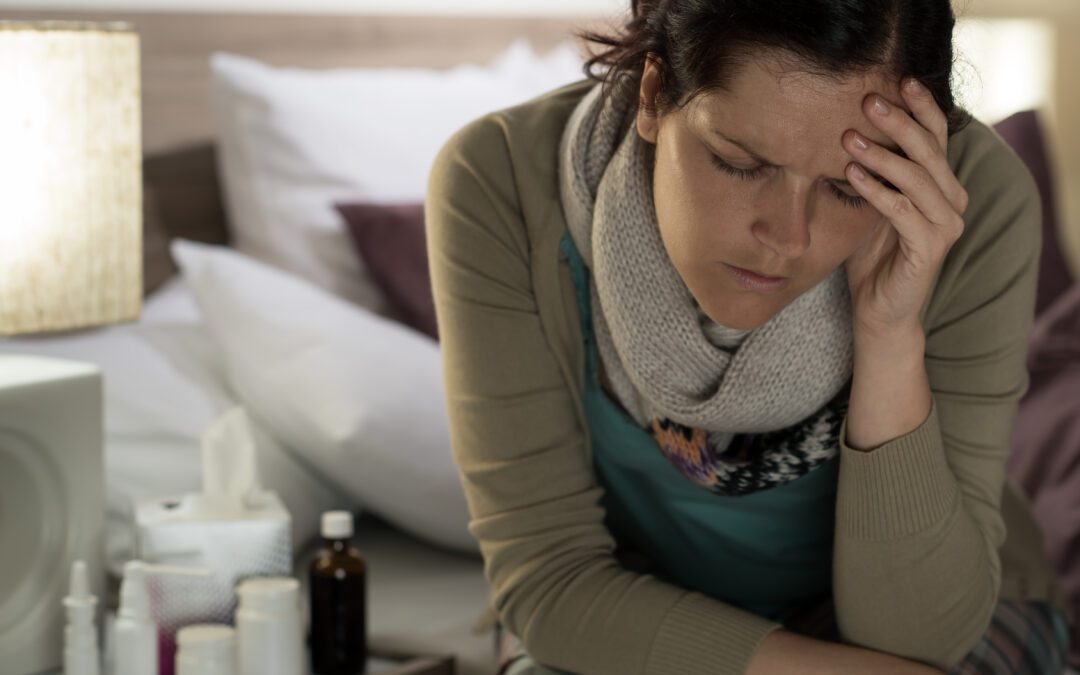 Ill woman with medicines suffering from flu headache in bedroom