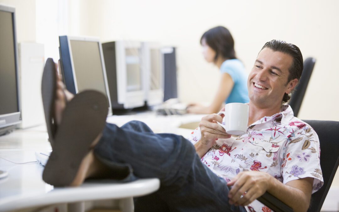 Man In Computer Room With Feet Up Drinking Coffee And Smiling